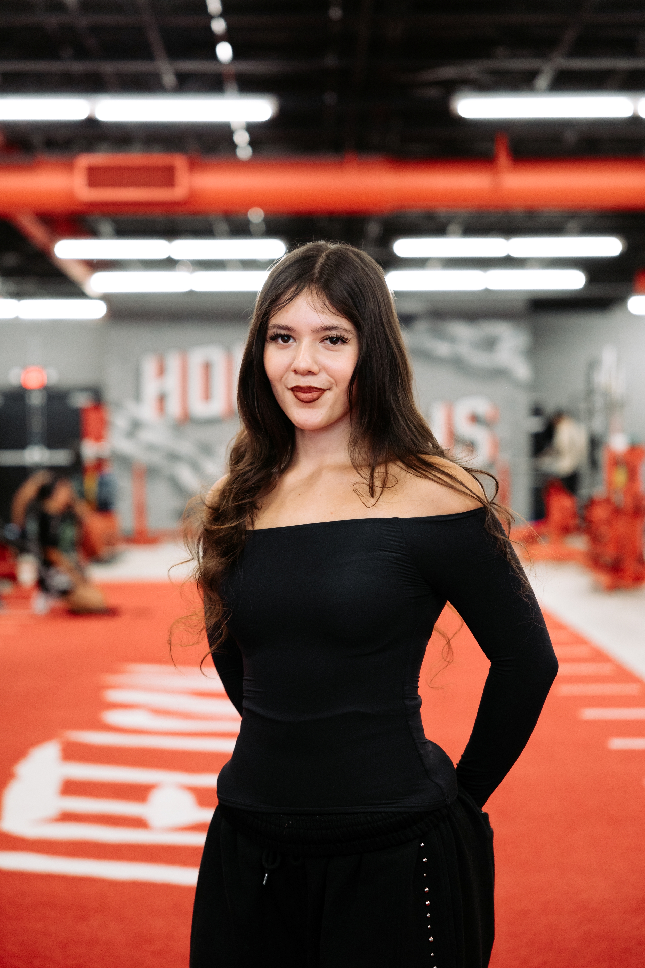 Sarah, of the House of Gains Oxnard crew, on the red turf in front of the House of Gains mural